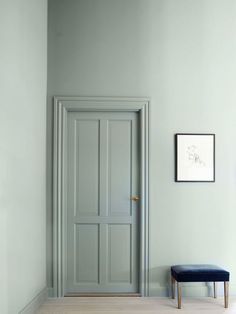 an empty room with a blue bench in the corner and a white wall behind it