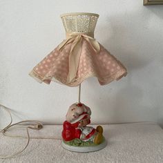 a lamp that is sitting on top of a table with a teddy bear under it