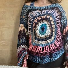 a woman wearing a crocheted sweater with an eye on it