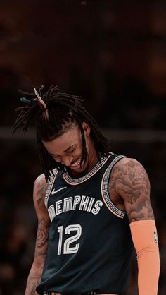 a basketball player with dreadlocks and tattoos on his head is looking down at the court