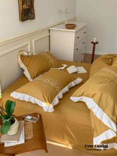 a bed with two pillows on top of it next to a night stand and nightstand