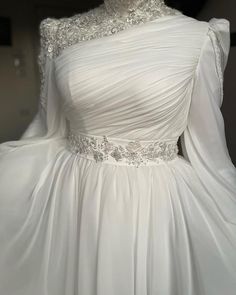 a white wedding dress with long sleeves and beading on the neckline is displayed