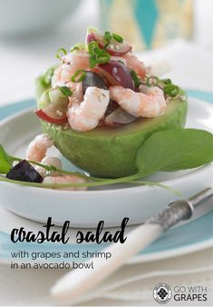 a close up of a plate of food on a table with text that reads coastal salad with grapes and shrimp in an avocado bowl