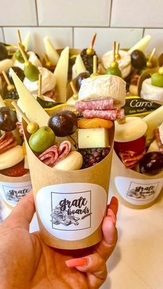 a person holding up an ice cream cup filled with different types of food