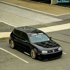 a black car with gold rims driving down the street