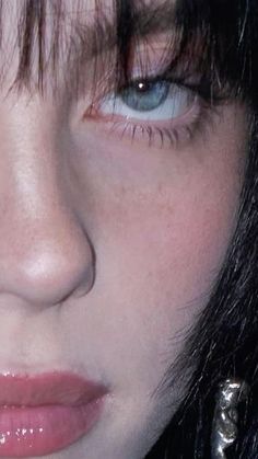 a close up shot of a woman's face with blue eyes and black hair