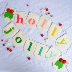 the word holiday spelled out in letters on a white tablecloth with red and green pom - poms