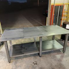 a metal table sitting inside of a warehouse next to some shelves and boxes on the floor