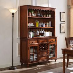 a dining room table and chairs in front of a wooden hutch with wine glasses on it