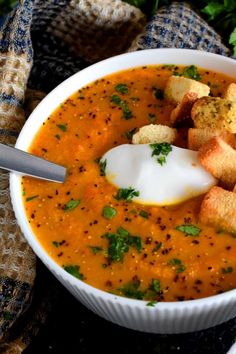 a white bowl filled with soup and croutons on top of a blue cloth