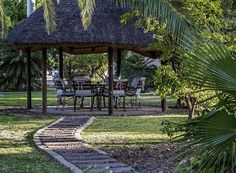 a gazebo in the middle of a park with tables and chairs around it, surrounded by palm trees