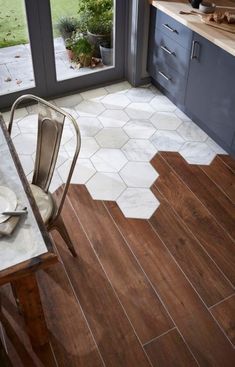 a kitchen with wooden floors and white hexagonal tiles on the floor, next to a glass door