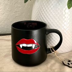 a black coffee mug with red lips on it and a keychain next to it