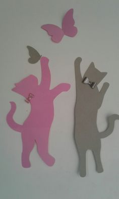 two cut outs of cats and a cat with a butterfly on its back, one in pink and the other in grey