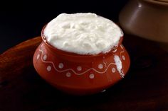 a red bowl filled with whipped cream on top of a wooden table