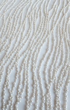 white pearls are on the surface of a quilted bed sheet with wavy lines in the background