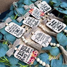 some tags that are on top of some blue leaves and plants with white beads hanging from them