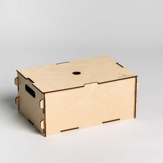 a wooden box sitting on top of a white floor next to a gray wall with a hole in it