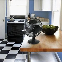 an air conditioner sitting on top of a wooden table next to a bowl of fruit