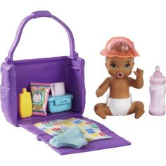 a baby doll sitting in front of a purple bag with items inside it and a bottle next to it