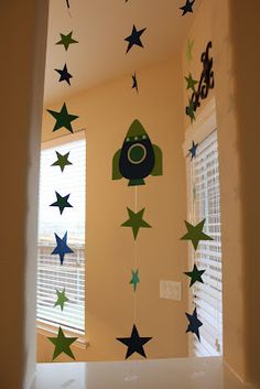 a room with stars hanging from the ceiling and curtains on the window sill,