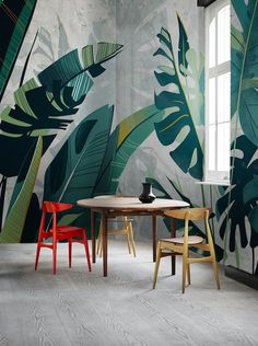 two chairs and a table are in front of a wall with tropical leaves on it