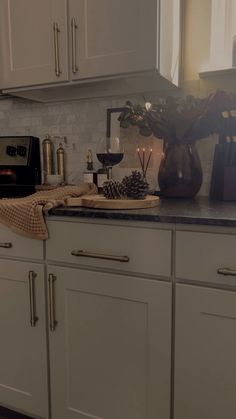 a kitchen with white cabinets and black counter tops is lit by candles on the stove