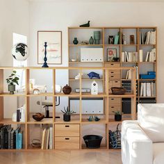 a living room filled with lots of furniture and bookshelves next to a white couch