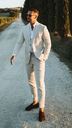 a man in a white suit is walking down the road