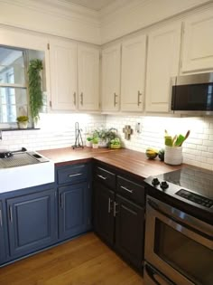 a kitchen with white and blue cabinets, wood floors and stainless steel stove top oven