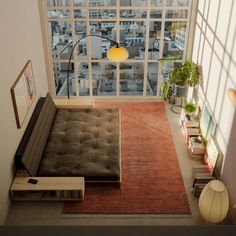 a living room with large windows and a couch in front of the window is an orange rug