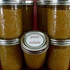 four jars filled with food sitting on top of each other next to a red ribbon