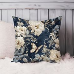 a blue pillow with white flowers and a butterfly on it