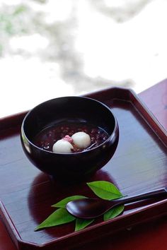 a bowl of soup with two eggs in it on a tray next to a spoon