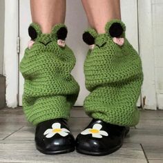 a close up of a person's legs wearing green crocheted shoes with flowers on them