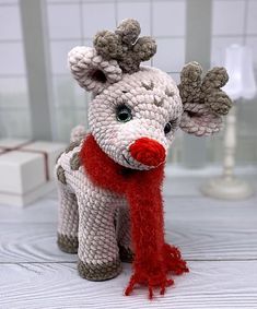 a knitted reindeer with a red scarf around it's neck on a table