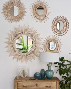 three sunburst mirrors mounted on the wall above a dresser with a lamp and potted plant