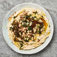 a white plate topped with hummus, olives and seasoning on top of a table