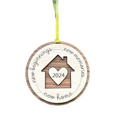 a wooden ornament with a house and heart in the center on a yellow ribbon