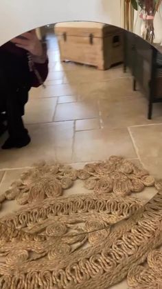 a person kneeling down on the floor in front of a rug that has been made out of rope