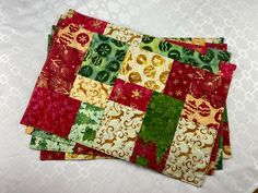 Christmas prints in cream, red and green - a combination that will look festive for the holiday season on your kitchen table! Also they are 17 1/2" wide and 12" deep and come as a set of four.  Please look over the pictures. The fabrics are hand-dyed Batiks in prints of a Christmas themed design that have a touch of metallic gold giving them a festive look. On the flip side, I used a batik print of people skiing on a gray background making them reversible. The last photo is a tree skirt that I made with the same fabrics. The material left over is the patchwork placemats.  Care instructions:  These placemats have a polyester batting which has less shrinkage than all cotton mats. Just wash them on gentle cycle, tumble dry on low for ten minutes, then lay them out flat to finish drying. There People Skiing, Patchwork Placemats, Quilted Patchwork, Batik Print, Christmas Placemats, Gold And Green, Batik Prints, Batik Fabric, Tree Skirt