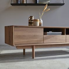 a wooden sideboard with two jars and a plant on it's top shelf