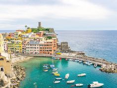 boats are docked in the blue water next to colorful buildings on an island near the ocean