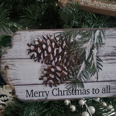 a wooden sign that says merry christmas to all with pine cones on it and snowflakes hanging from the branches