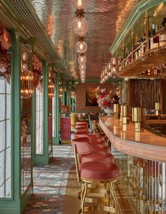 the bar is decorated with gold and red leather chairs, chandeliers, and wine bottles