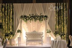 a white couch sitting on top of a stage next to a table covered in flowers