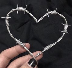 a hand holding a heart shaped barbed wire