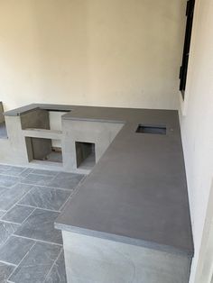 two concrete benches sitting next to each other on top of a stone floor in front of a wall