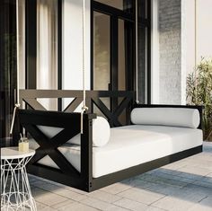 a black and white swing bed on a porch with a table in front of it