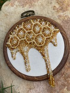 a wooden frame holding a gold beaded tree ornament on a stone surface